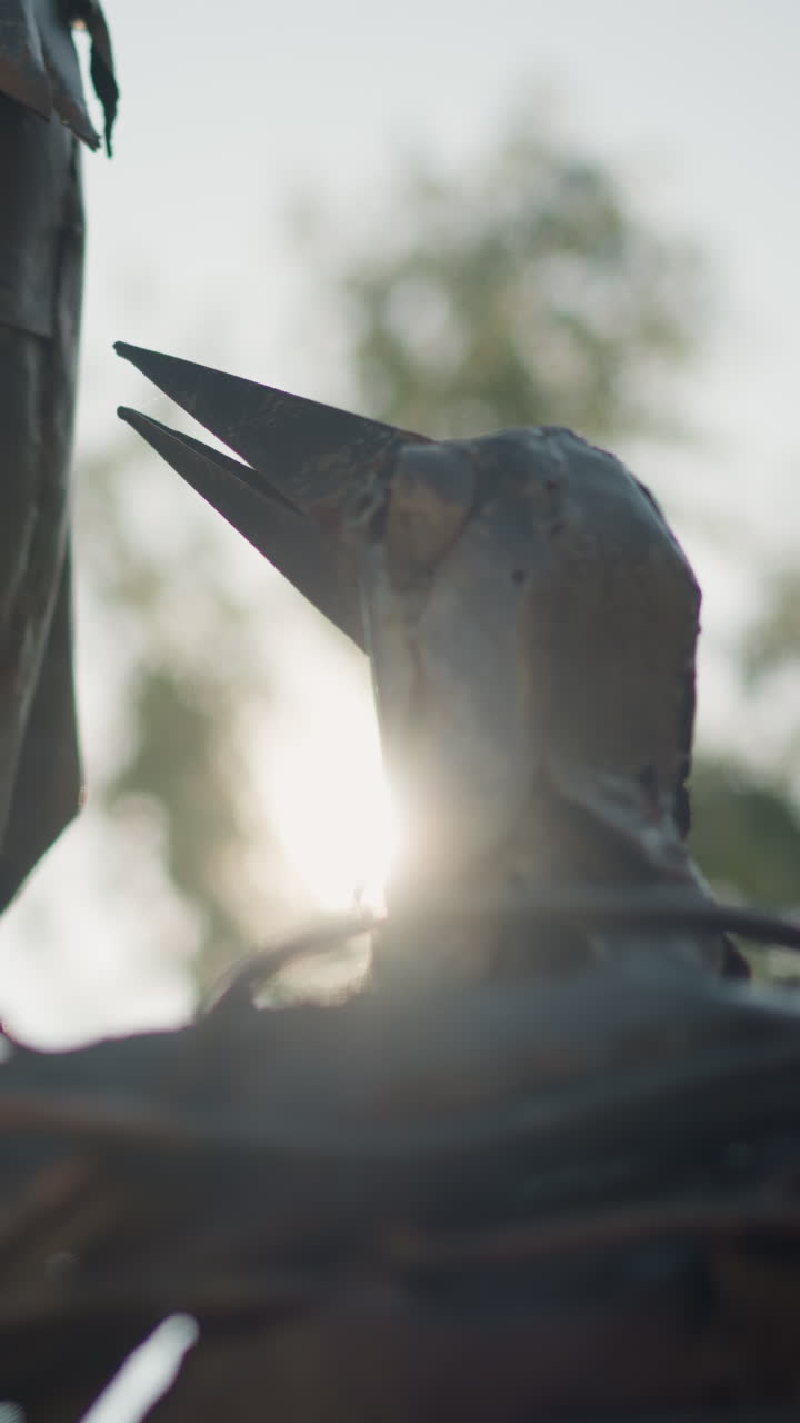 둥지에 있는 역광 금속 새, 녹슨 부리와 질감 있는 녹청을 보여주는 클로즈업, 부드러운 보케 햇빛, 짜여진 와이어 횃대, 흐릿한 정원 나무 배경, 영화 같은 분위기, 정원 관리인