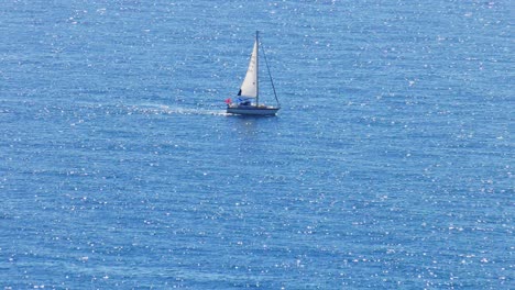 yacht sailing on wide blue sea with sparkling waves, mediterranean