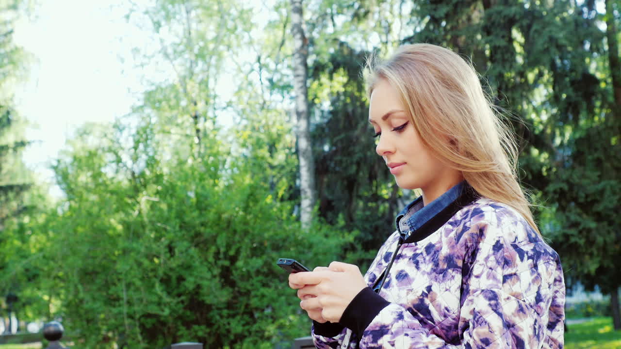 도시를 걷는 매력적인 여성은 스마트폰을 즐긴다 prores 422 10 bit