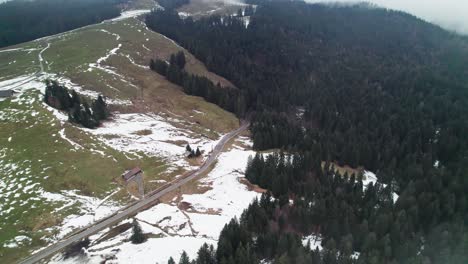 Drone-flying-over-melting-snow-and-forest-in-the-high-Alps-in-Sattelegg,-Switzerland