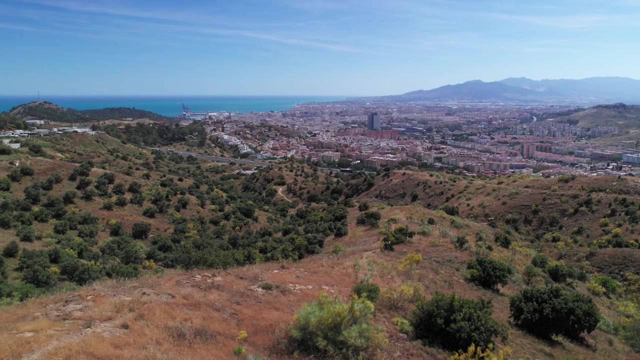 Ilmakuva Malagan kaupungista ja ympäröivistä kukkuloista, hitaasti sivuttain liikkuen, Andalusia, Espanja.