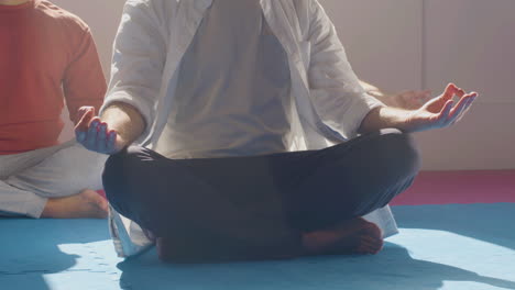 unrecognizable people sitting in lotus position on floor