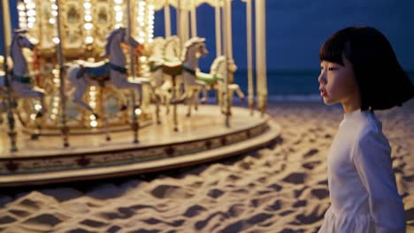 girl walking on the beach at night near a carousel