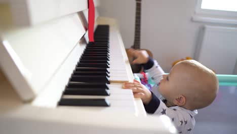 a cute baby boy trying to play a big piano while standing up. 4k