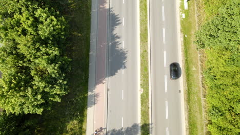 Cars-Passing-Through-Highway-Between-Thick-Forest-Landscapes-In-Witomino-Poland---aerial-shot