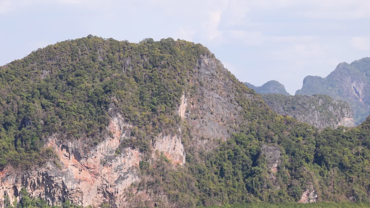 A serene view of lush, green mountains under a bright sky, captured with smooth camera movement in Phang Nga, Thailand