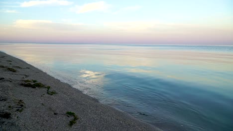 static shot from shore of calm waves on the sunrise sea