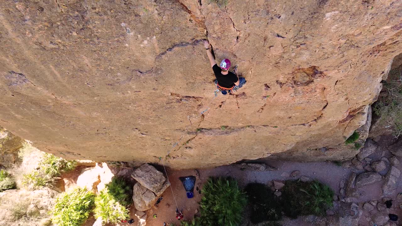 Luftaufnahme eines Mannes beim Felsklettern und eines Sportlers beim Abseilen am Berg in La Panocha, El Valle Murcia, Spanien, mit einer Frau, die sich einen Berg hinabseilt und einen großen Felsen erklimmt.