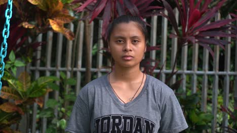 hardworking and kind filipina orphan girl looking sadly and lonely into the camera at the orphanage home in the philippines - medium shot