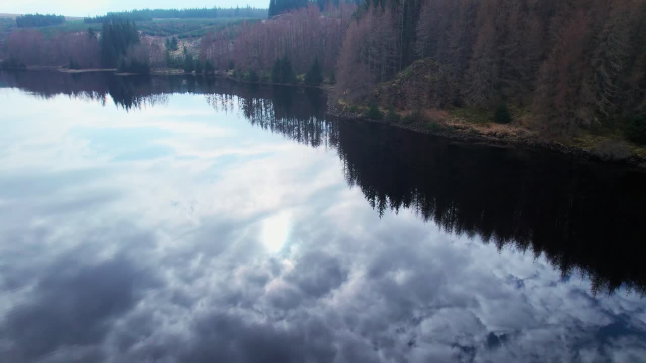 Aerial drone flying above calm water reflecting clouds, tilt up reveals landscape, Loch Lochy, Spean Bridge, Scotland