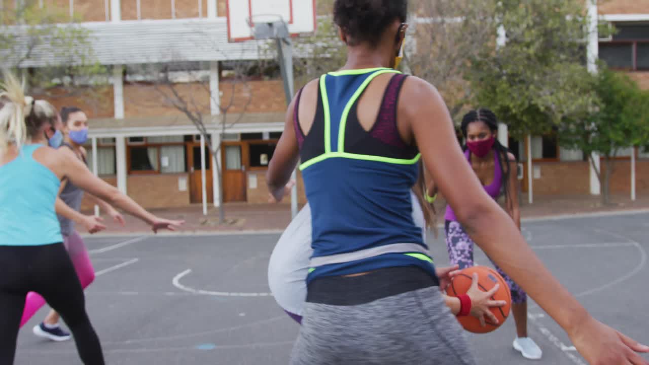 equipo de baloncesto femenino diverso con máscaras faciales jugando partido, marcando goles
