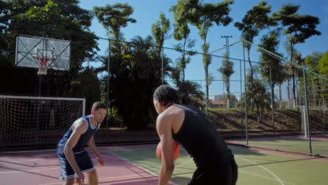young men playing basketball on an outdoor court
