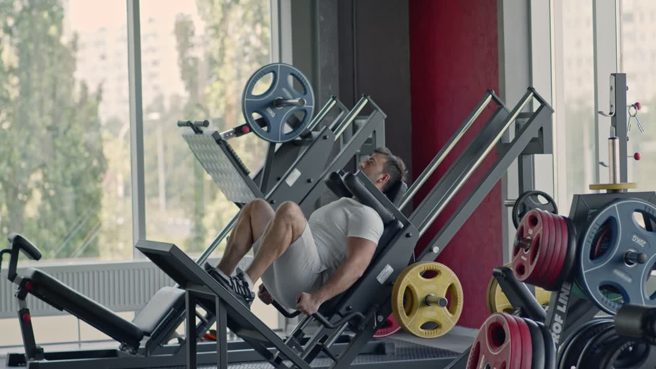 Man Exercising on Leg Press Machine in Gym