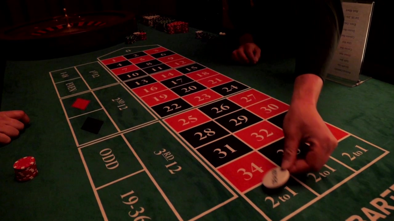 Vista ravvicinata di un tavolo da roulette durante un elegante evento a tema casinò con una mano che piazza una scommessa.