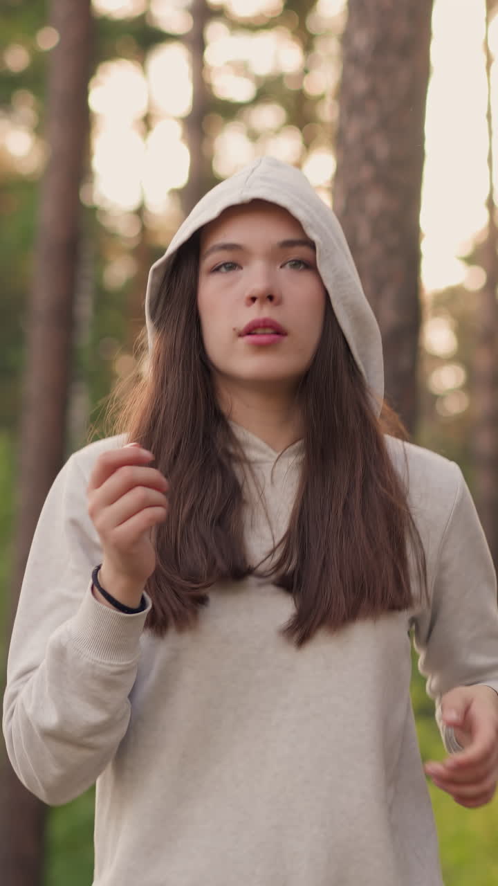 여자 운동 선수는 숲에서 달리는 후드를 착용합니다. 체력을 향상시키고 몸 모양을 유지합니다. 은 날 야생 자연에 둘러싸인 활발한 조