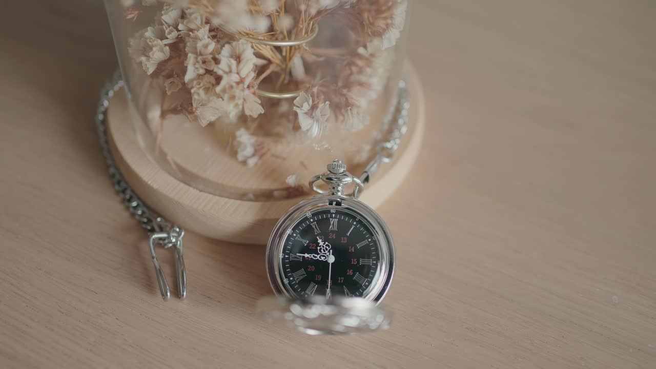 Classic pocket watch with chain placed near preserved dried blooms