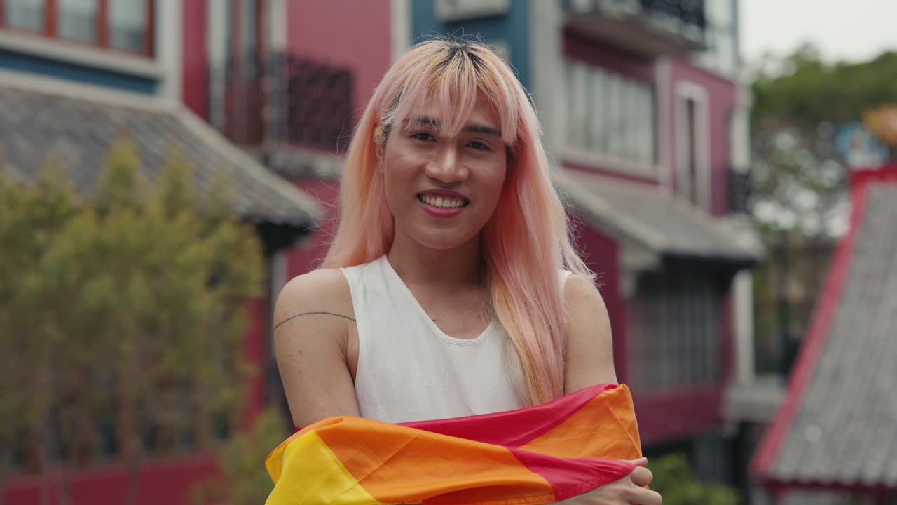 Proud LGBTQ+ person holding a rainbow flag in a city street