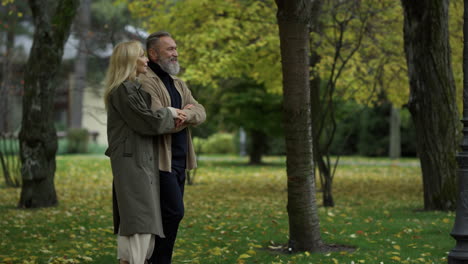 Toma-Lateral-De-Una-Hermosa-Pareja-De-Ancianos-Caminando-Lentamente-Por-El-Sendero-En-El-Parque-De-Otoño.