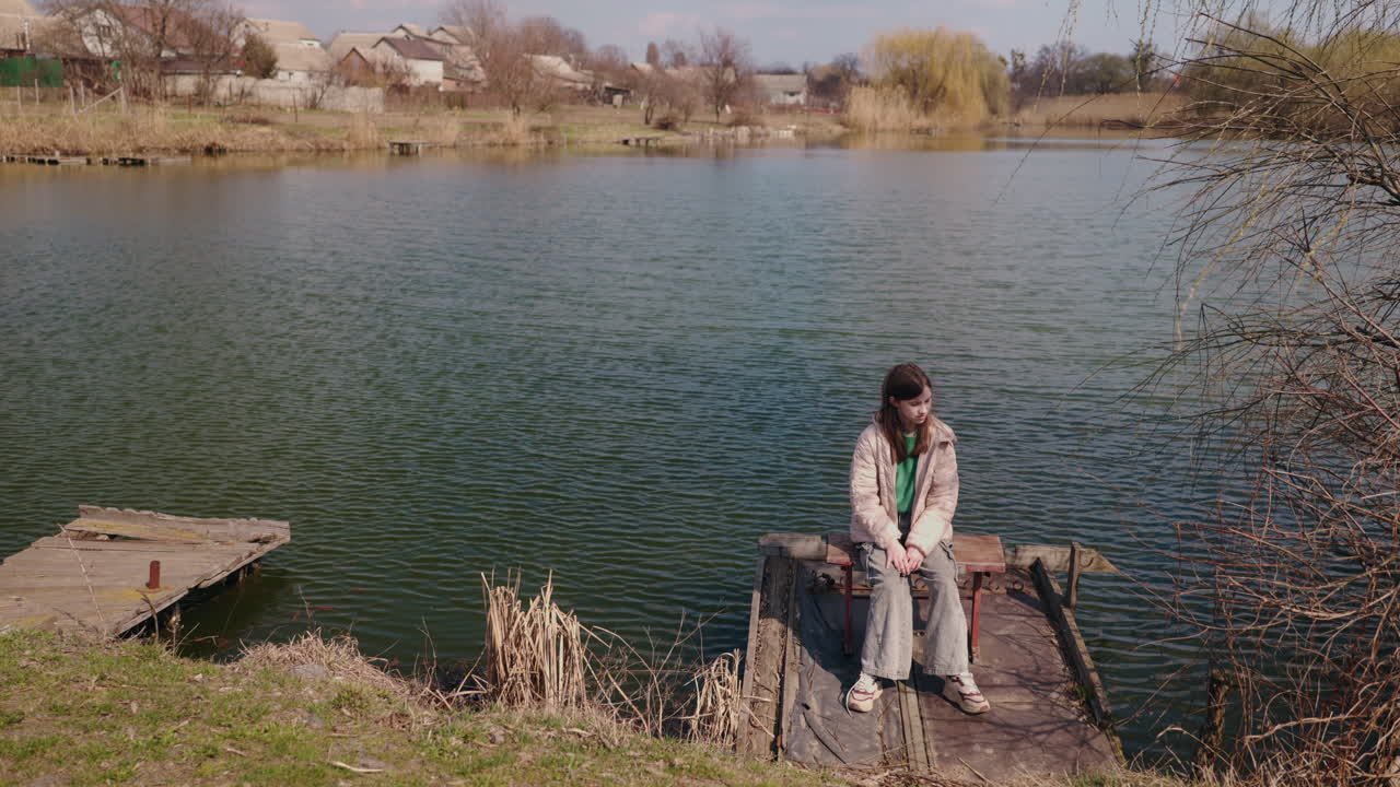Girl Sitting on a Wooden Dock by a Lake