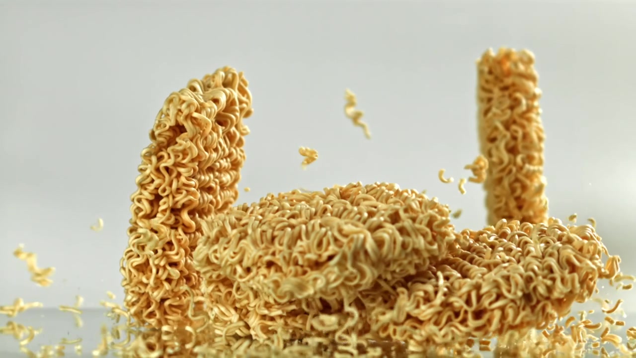 Noodles ramen istantanei secchi che cadono e si rompono al rallentatore.