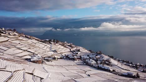 aerial view over typical swiss village in lavaux vineyard covered by snow the alps and lake leman in the background