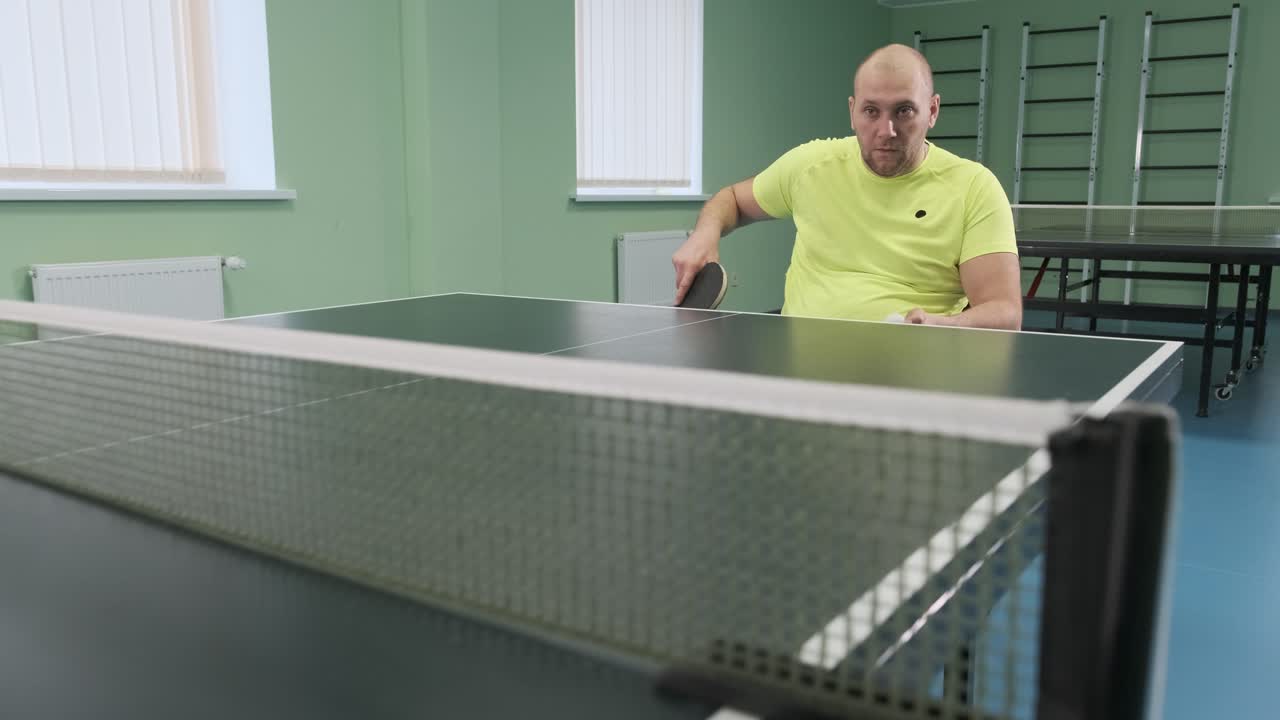un hombre en silla de ruedas juega ping pong. personas con discapacidad juegan tenis de mesa. rehabilitación de discapacitados. deporte paralímpico.