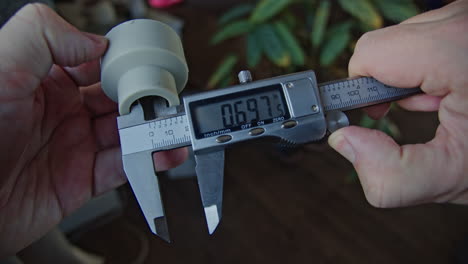 manos de ingeniero que utilizan una pinza de vernier para escalar la pieza metálica,