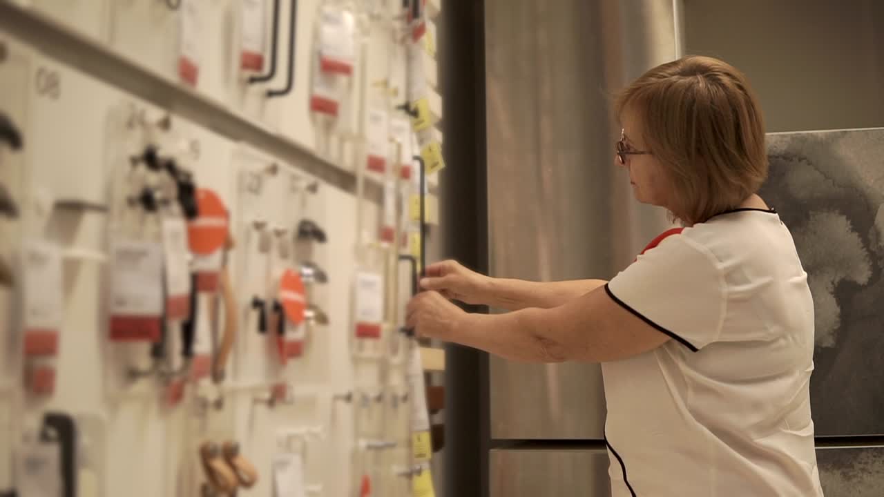 mujer eligiendo manijas de gabinete en una tienda de mejoras para el hogar