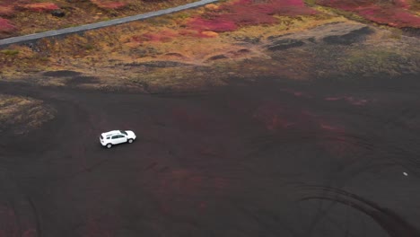 white suv car driving on volcanic black sand beach in nordic iceland