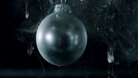 a silver shiny sphere spinning in a dark environment