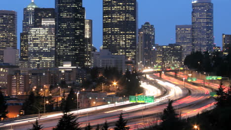 Als-Sich-Die-Goldene-Stunde-Zur-Nacht-Verdunkelt,-Verschwimmt-Der-Beschleunigte-Verkehr-Zu-Lichtstreifen-Vor-Einer-Beleuchteten-Skyline-Von-Seattle-Sea