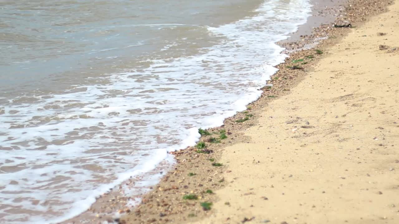 모래와 바위 해변에 부서지는 파도