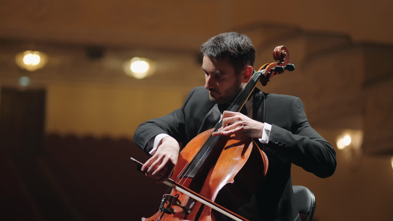 el talentoso violonchelista está tocando el violonchelo en la escena en la sala de conciertos violoncheleiro en la orquesta sinfónica
