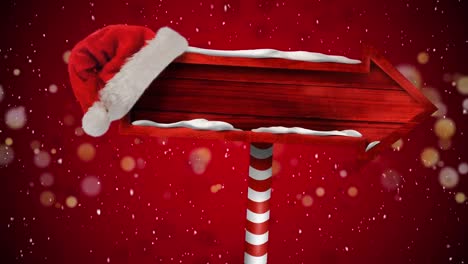 Animation-of-christmas-sign-with-copy-space-and-santa-hat-over-snow-falling-on-red-background