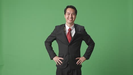 un hombre de negocios asiático sonriendo cálidamente en el fondo de la pantalla verde en el estudio