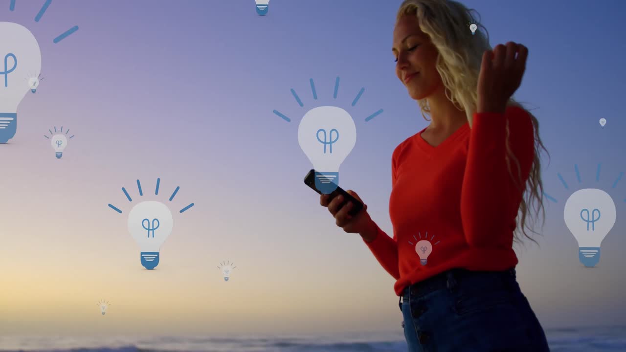 Animation of bulb icons over midsection of caucasian woman using smartphone at sunset
