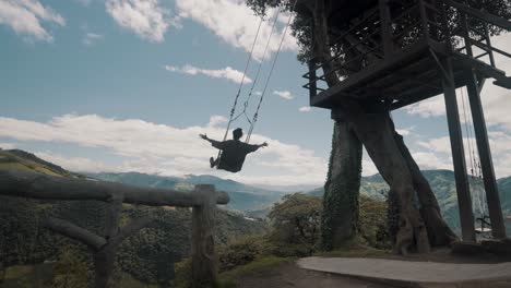 portrait of an adventurous man swinging at la casa del arbol tourist attraction in ecuador