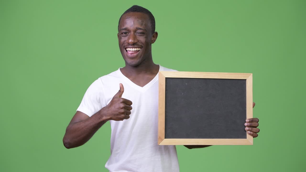 Young African man showing blackboard and giving thumbs up