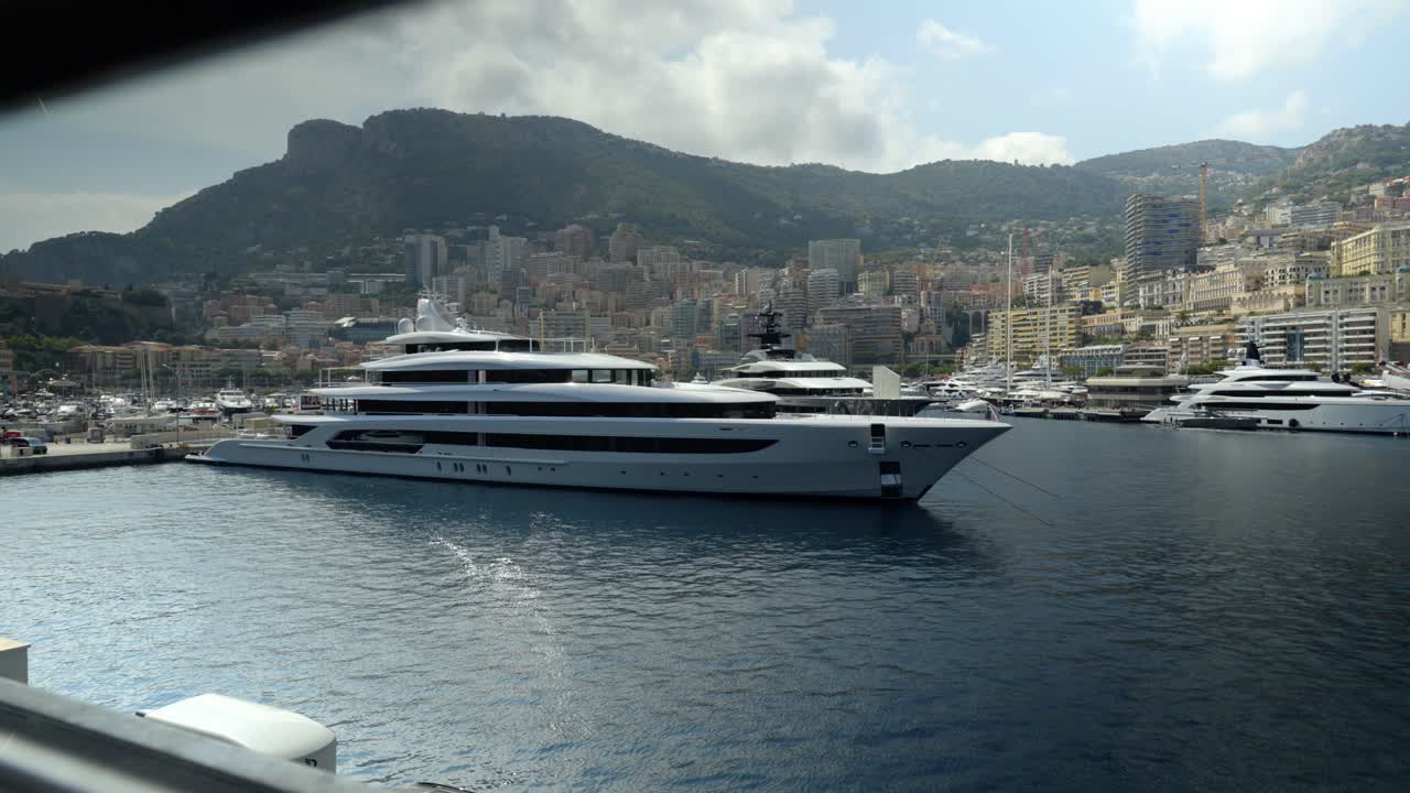 Luxury yachts docked in Monaco's harbor with city and hills in the background