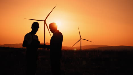 engineers discussing wind farm project at sunset