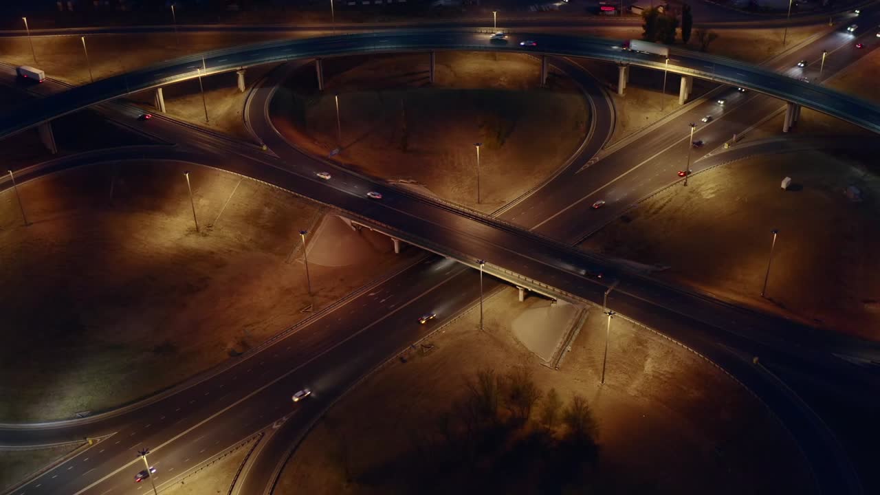Intersection circle transport junction at night city road with car traffic, aerial view from drone