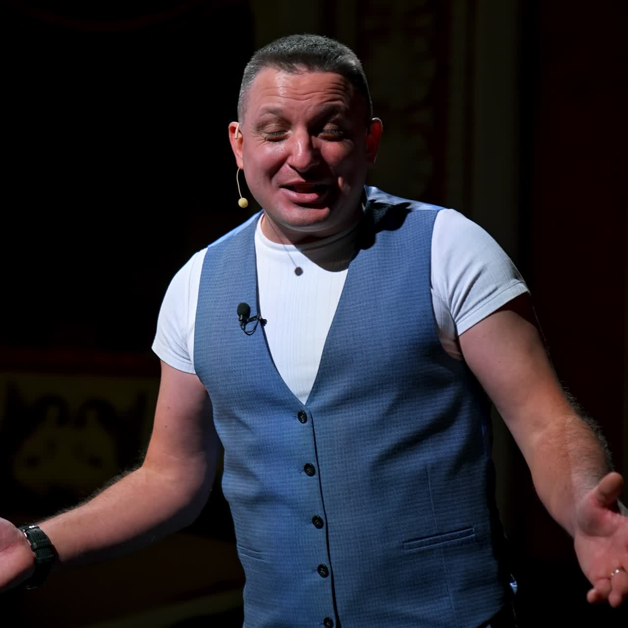 Man in suit speaking jokes in micropphone standing on stage. Funny performance. Comedian in good humor speaks to the audience