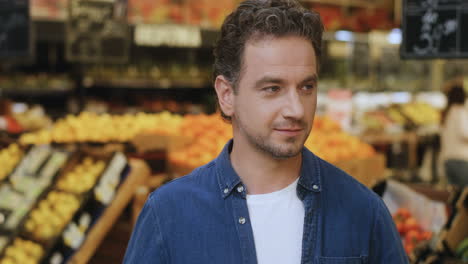 portrait shot of the young handsome man smiling happily to the camera at the grossery supermarket