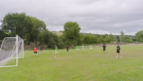 multiracial male soccer players playing soccer, running after and passing ball on pitch