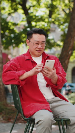 Asian-middle-aged-man-using-smartphone-typing-text-messages-in-social-media-application-online