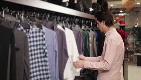 male shopper is choosing a shirts in a shop in a shopping mall