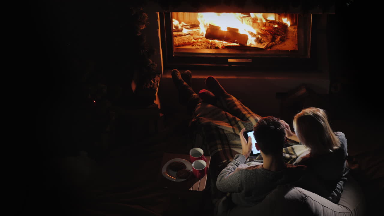 hombre y mujer usan una tableta en su sala de estar cerca de la vista superior de la chimenea