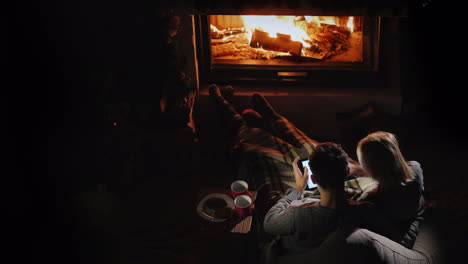 man and woman use a tablet in their living room near the fireplace top view