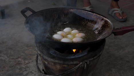 motion chef uses spatula to add duck eggs on rusty frying pan outdoors - street food