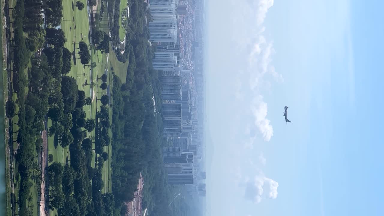 Breathtaking aerial stock footage captures a massive airplane descending towards Singapore airport, framed by Marina Bay Sands, with the city's skyscrapers and lush gardens in the backdrop